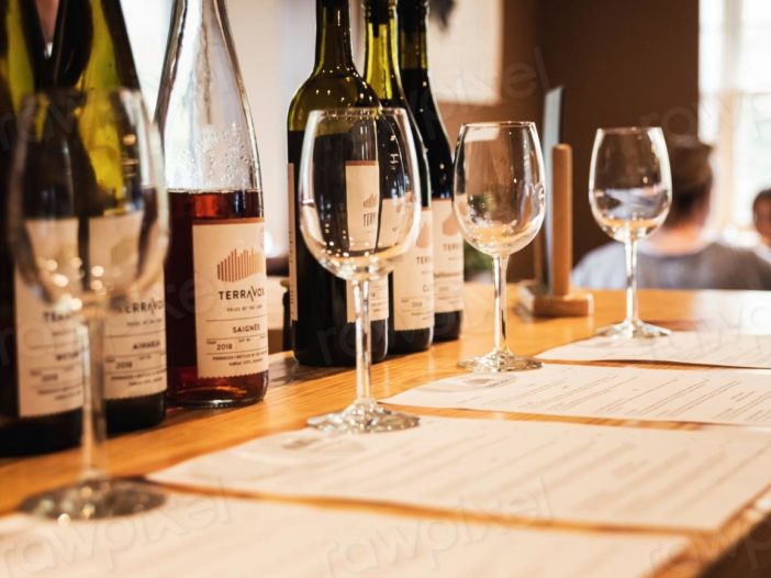 Verres et bouteilles de vin disposés sur un comptoir pour une dégustation, illustrant les bases de l'art de la dégustation du vin : observation, olfaction et dégustation en bouche pour apprécier pleinement ses arômes et sa structure.