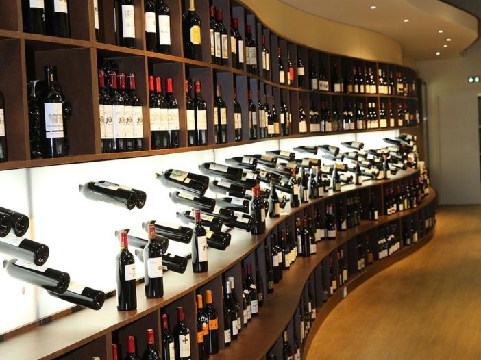 Cave à vin moderne avec une large sélection de bouteilles disposées sur des étagères élégantes. Mais il est important d'avoir les clefs pour choisir une bonne bouteille de vin avant de se rendre chez le caviste.