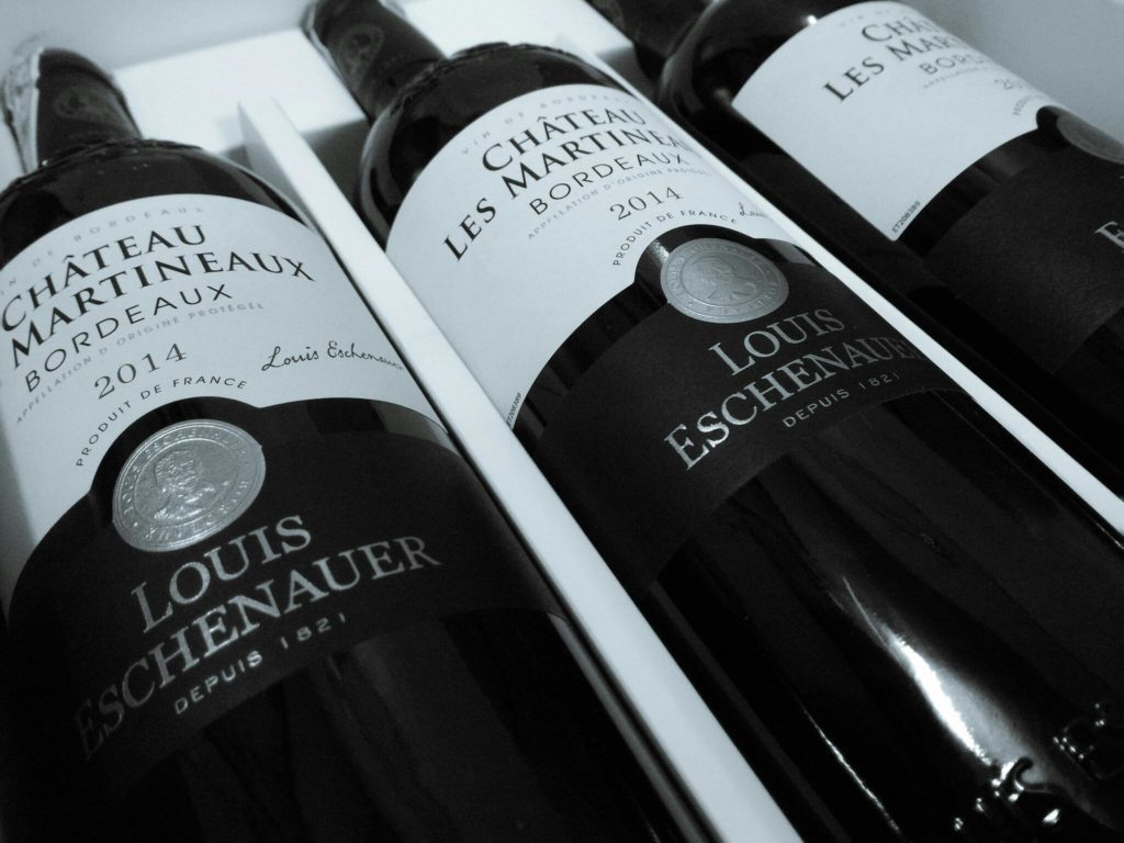Gros plan sur des bouteilles de vin Château Les Martineaux Bordeaux 2014, mettant en avant l'étiquette Louis Eschenauer. L'étiquette de vin joue un rôle essentiel en informant sur son origine, son appellation et son producteur, des éléments clés pour évaluer sa qualité avant dégustation.