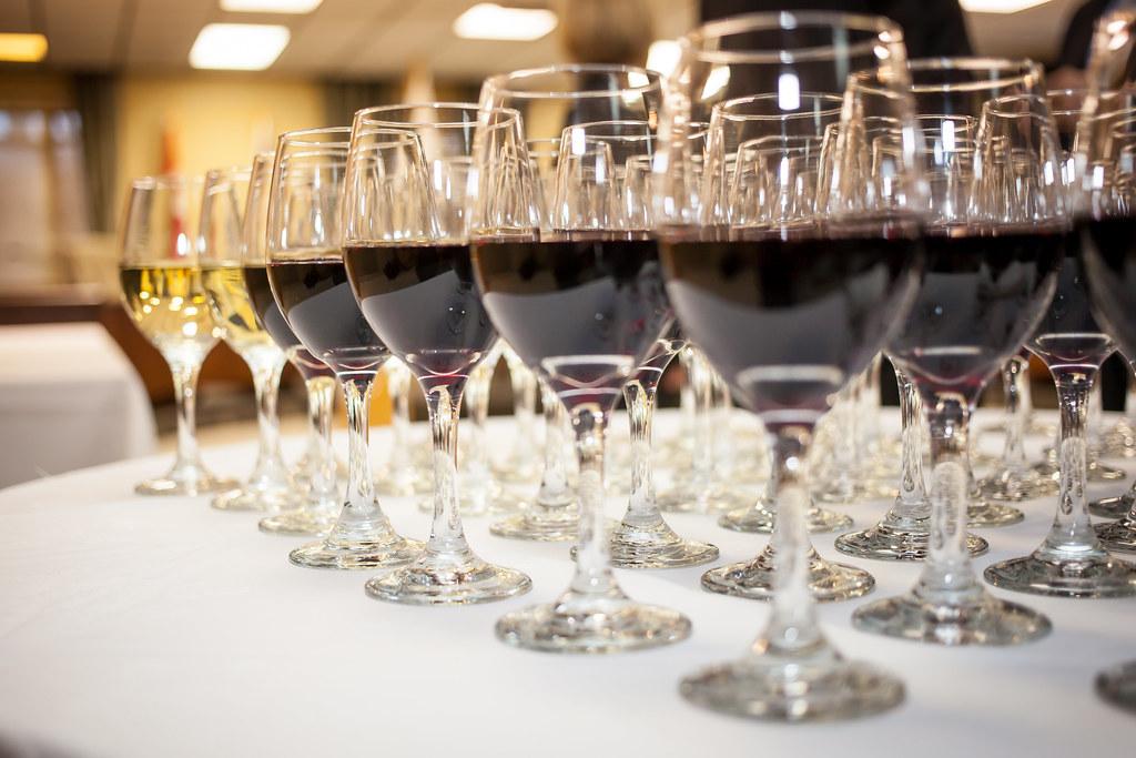 Rangée de verres remplis de vin rouge et blanc, illustrant l'importance de l'observation visuelle en dégustation : analyser la couleur, la brillance et les reflets pour évaluer l'âge et la qualité du vin.