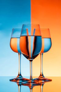 Image artistique inspirée du pop art mettant en scène trois verres à vin dans un jeu de reflets et de couleurs vives et contrastées, bleu et orange. Cette composition graphique revisite le vin comme un objet du quotidien transformé en icône artistique.