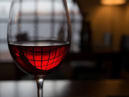 Un verre de vin rouge capturant la lumière et révélant sa robe éclatante. La couleur et la brillance de la robe du vin sont des critères essentiels pour évaluer sa qualité, son âge et son potentiel de dégustation.