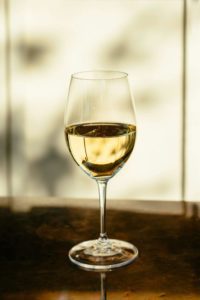 Un verre de vin blanc posé sur une table, illuminé par une lumière douce, illustrant la fraîcheur et la diversité aromatique du vin blanc.