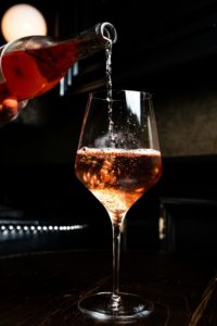 Un vin rosé est versé dans un verre à pied, révélant sa teinte lumineuse et sa finesse.